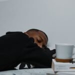 a man sleeping on a bed next to a stack of books