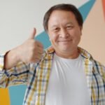 Smiling man gives a thumbs up gesture.