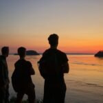 a group of people standing next to a body of water