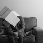a person sitting on a couch with a book on their head
