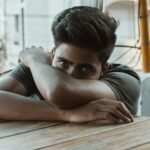 man in black t-shirt leaning on wooden table
